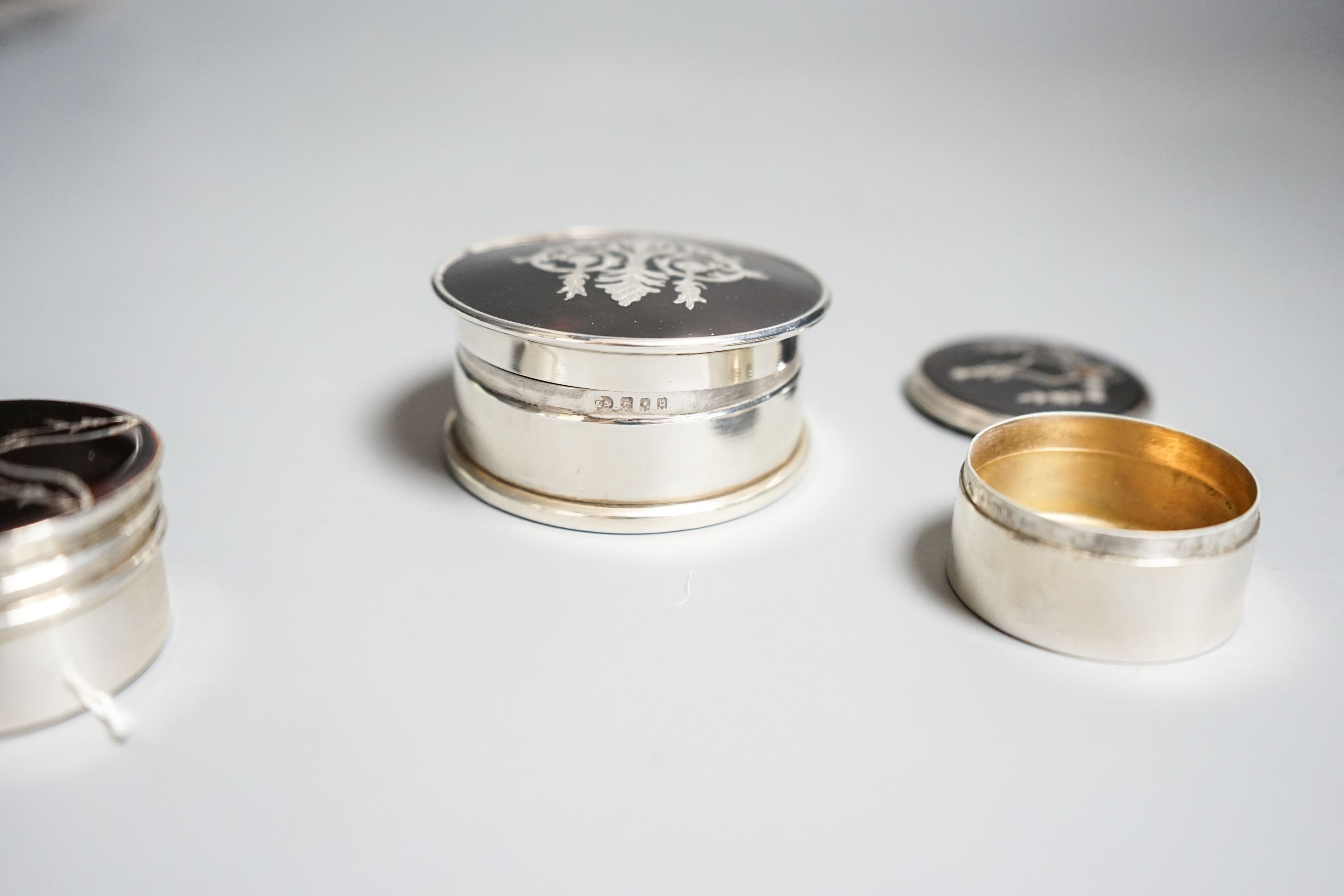 Three assorted early 20th century silver and tortoiseshell pique circular boxes and covers, including William Comyns, largest 63mm.